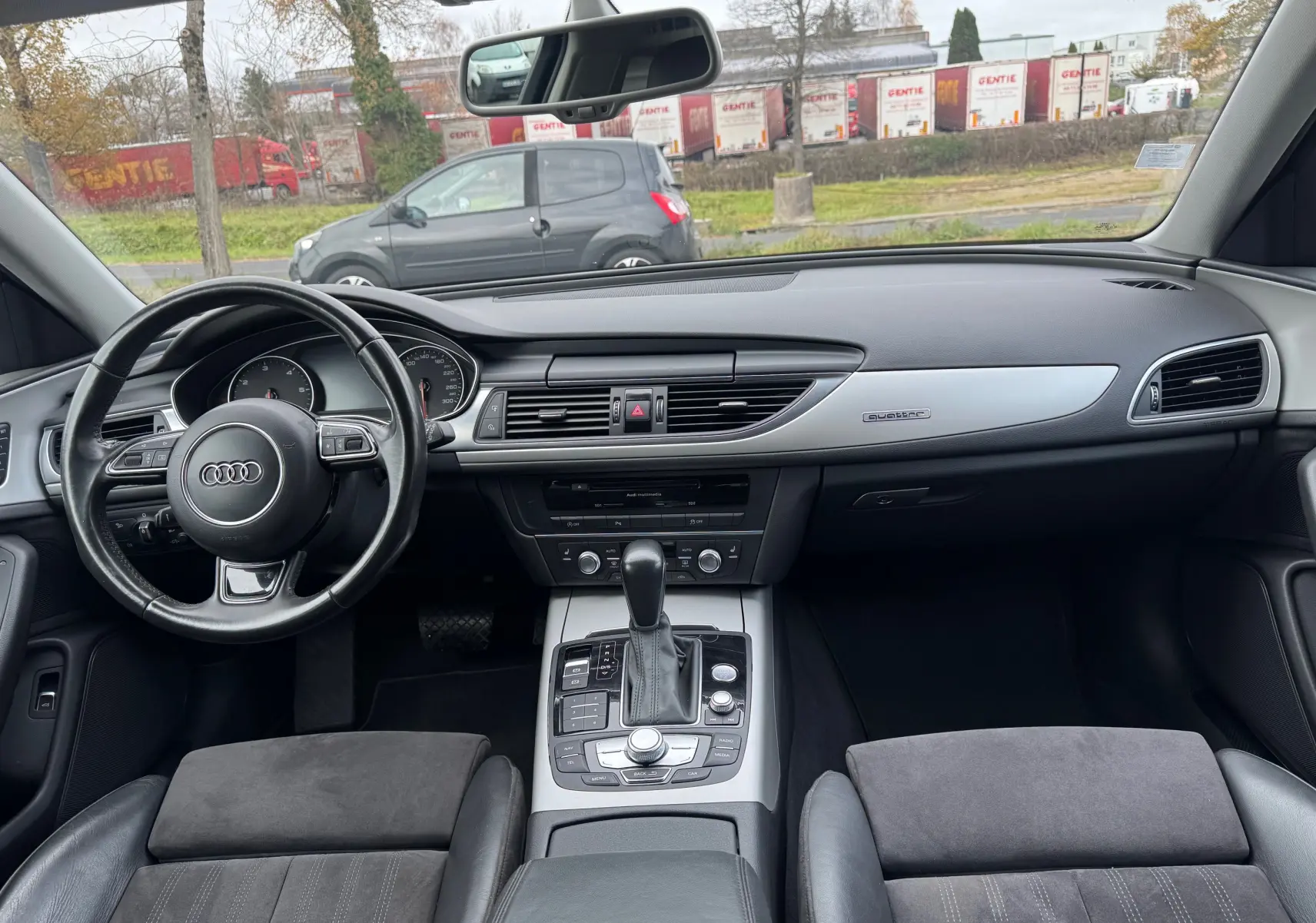 Vue intérieure de l'Audi A6 Avant 2015, tableau de bord et console centrale avec volant cuir et finition aluminium Quattro.