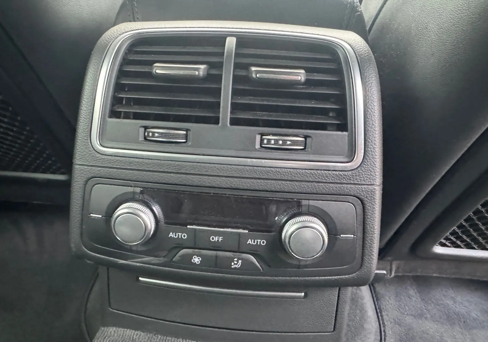 Détail de la console arrière noire de l’Audi A6 Avant 2015 avec commandes de climatisation et aérateurs.
