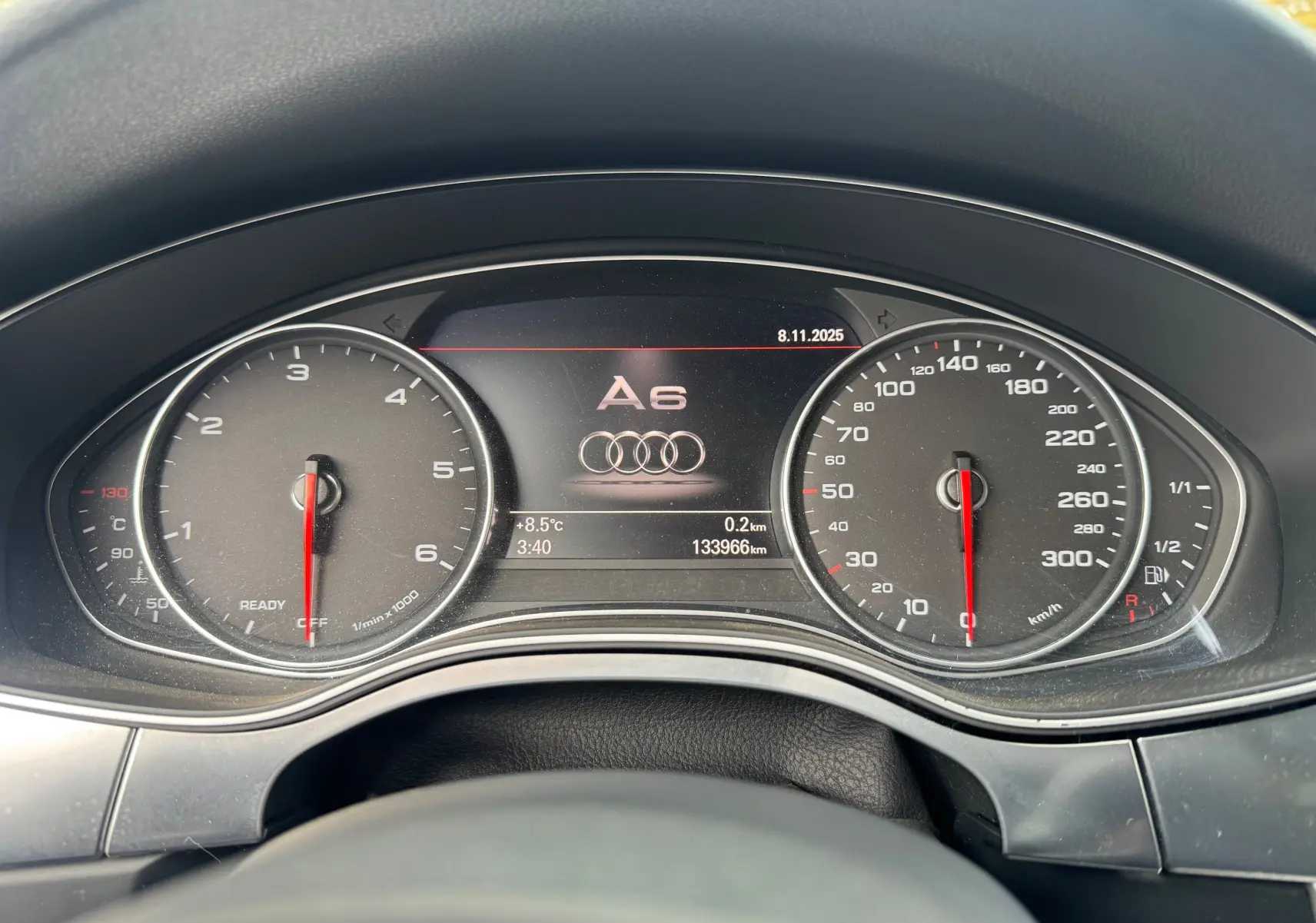 Vue rapprochée du tableau de bord numérique de l'Audi A6 Avant noir, affichant compte-tours, vitesse et logo central.