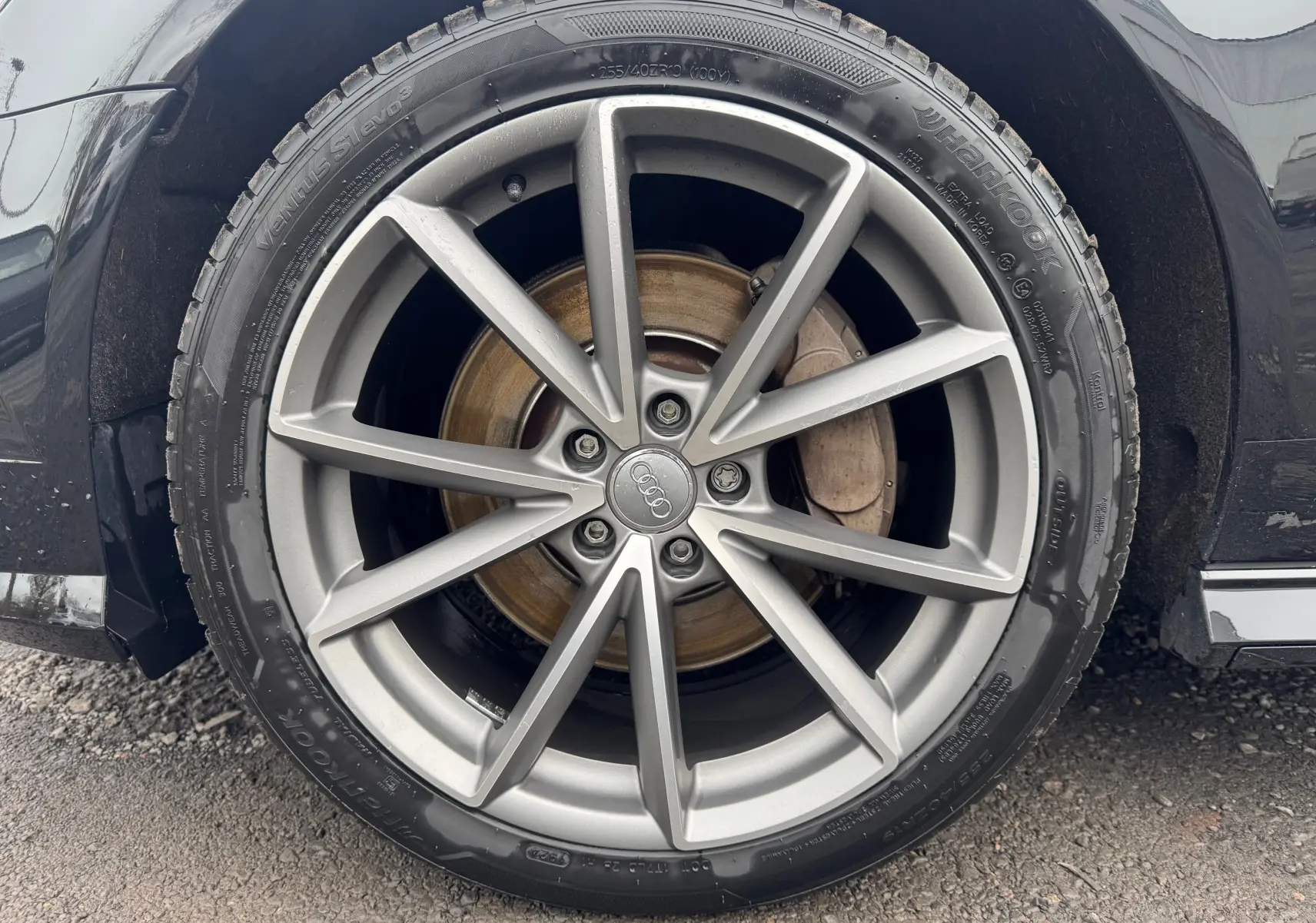 Gros plan sur la jante alliage argentée de l'Audi A6 Avant noire, mettant en valeur le logo Audi au centre.