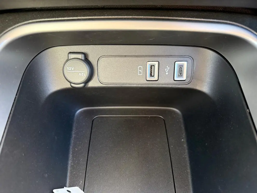 Gros plan sur la prise 12V et ports USB dans la console centrale noire du Jeep Avenger blanc 2025.