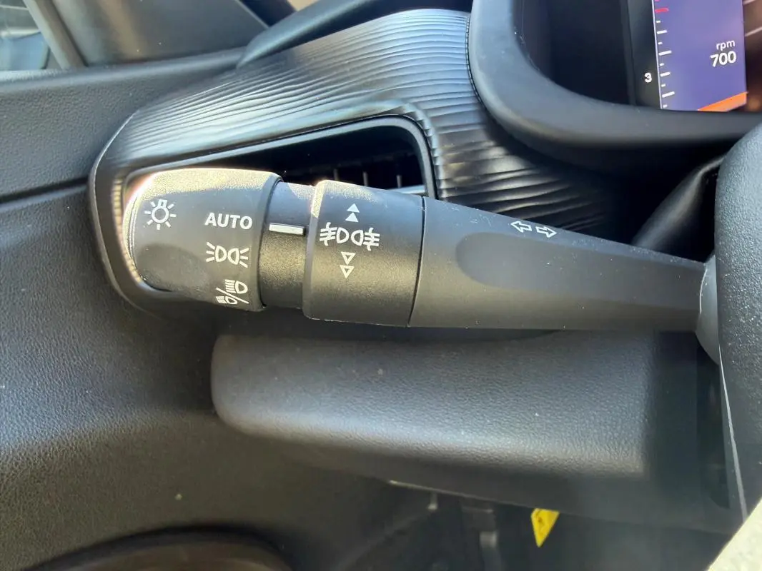 Gros plan sur la commande des phares et clignotants du Jeep Avenger blanc, côté gauche du volant.