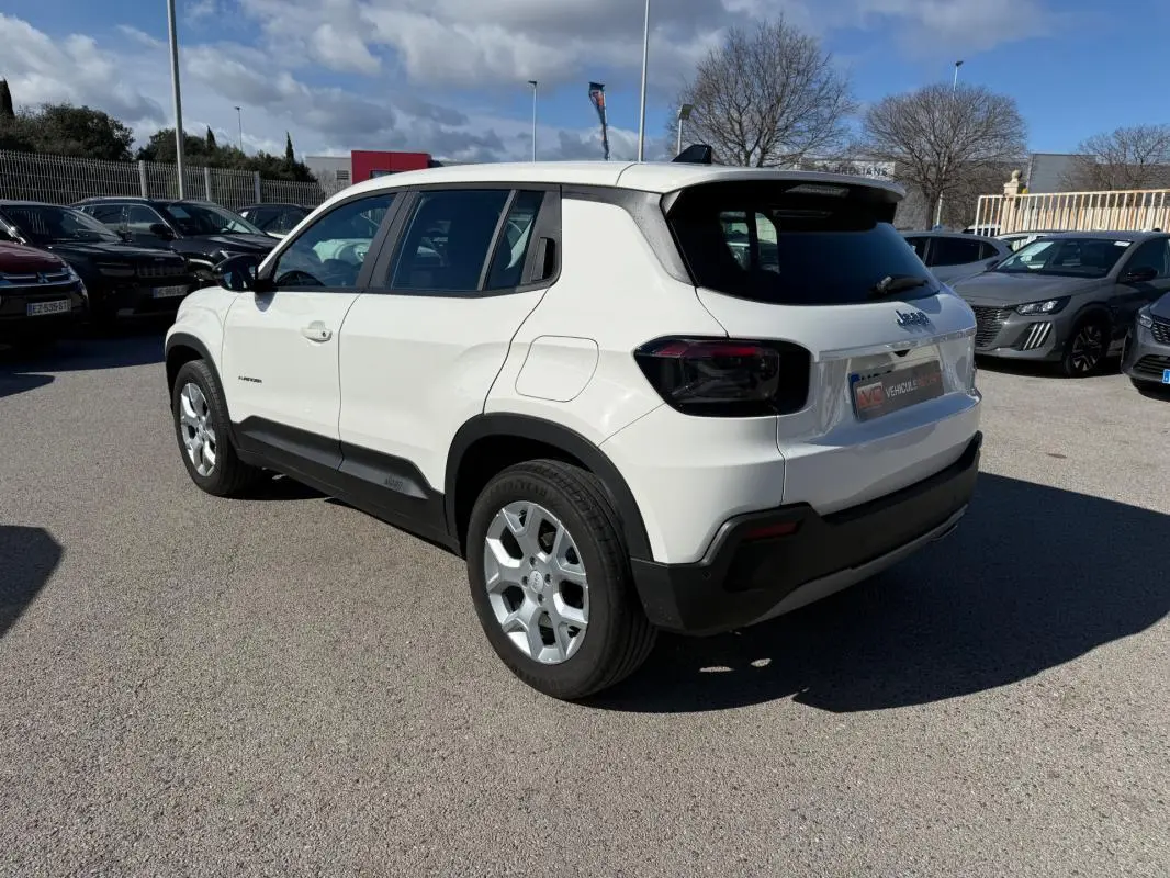 Jeep Avenger blanc en vue 3/4 arrière droit, avec jantes alliage 17 pouces et vitres arrière teintées.