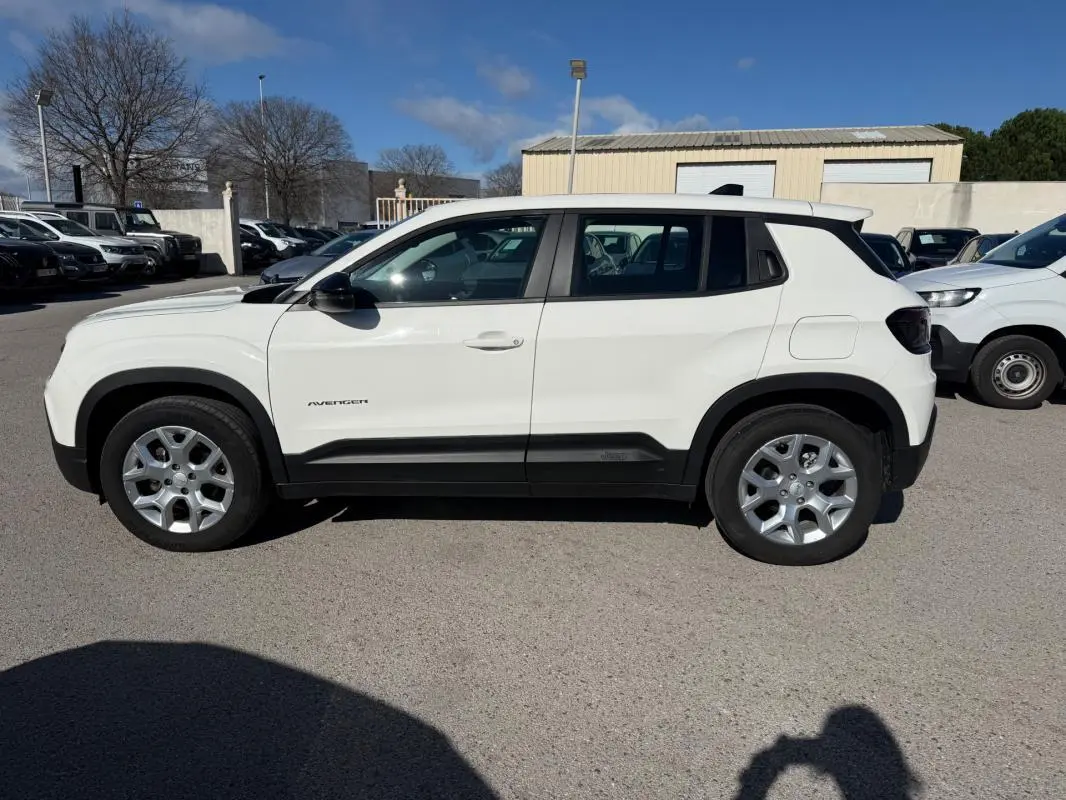 Profil côté gauche d'un Jeep Avenger blanc 2025 avec jantes alliage 17 pouces sur parking extérieur.