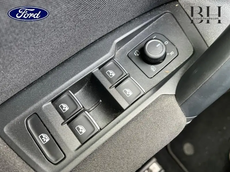 Gros plan sur les commandes de lève-vitres et rétroviseurs côté conducteur d'un Volkswagen Tiguan noir intense nacrée.