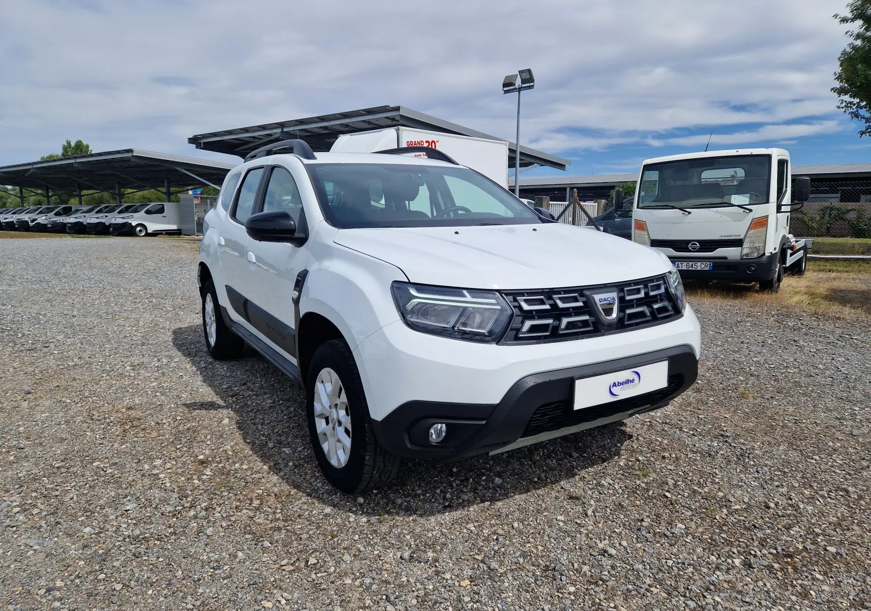Dacia Duster blanc vue 3/4 avant droit, SUV 4x4 avec calandre noire et jantes alliage 16 pouces.