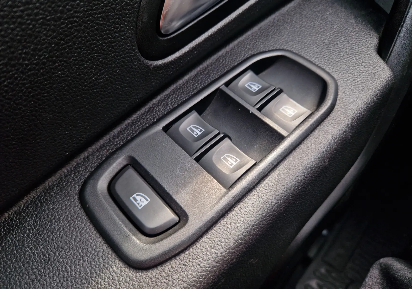 Gros plan sur les commandes électriques des vitres côté conducteur du Dacia Duster blanc 4x4 2022.