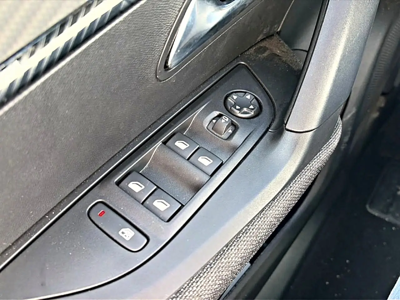 Détail des commandes des vitres électriques côté conducteur sur porte intérieure grise du Peugeot 2008 2025.