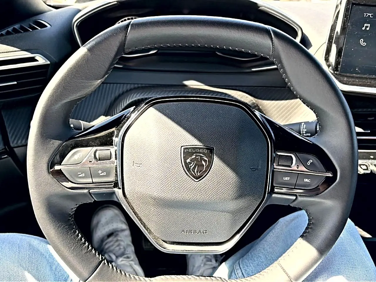 Vue rapprochée du volant multifonction noir du Peugeot 2008 1.2 100 style avec logo lion central, intérieur gris.