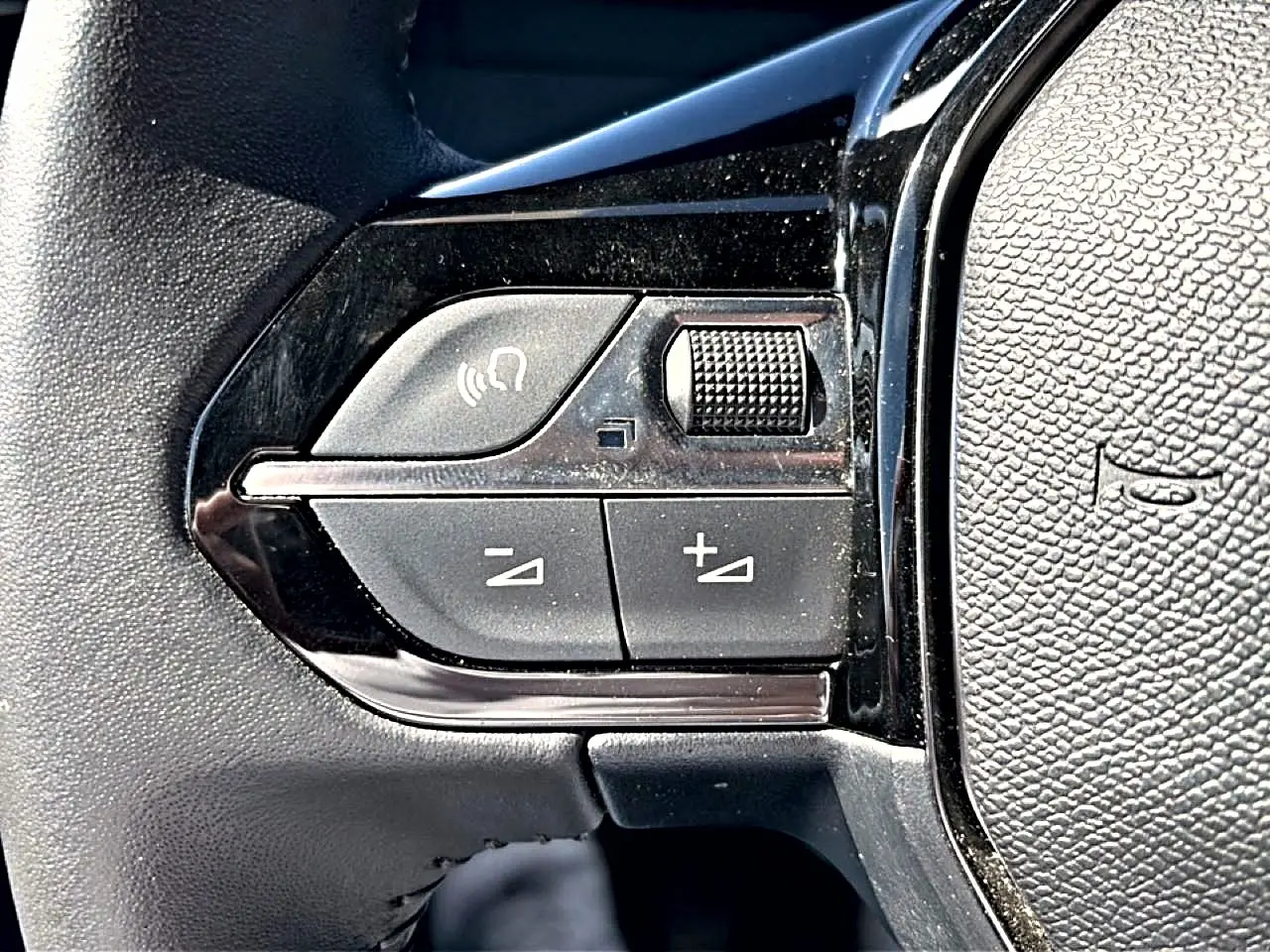 Gros plan sur les commandes noires du volant multifonction du Peugeot 2008 gris, version 1.2 100 style.