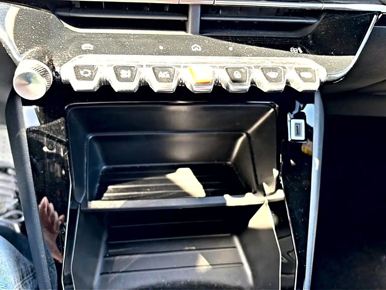 Gros plan sur la console centrale noire brillante du Peugeot 2008 1.2 100 style avec rangements et boutons de commande.