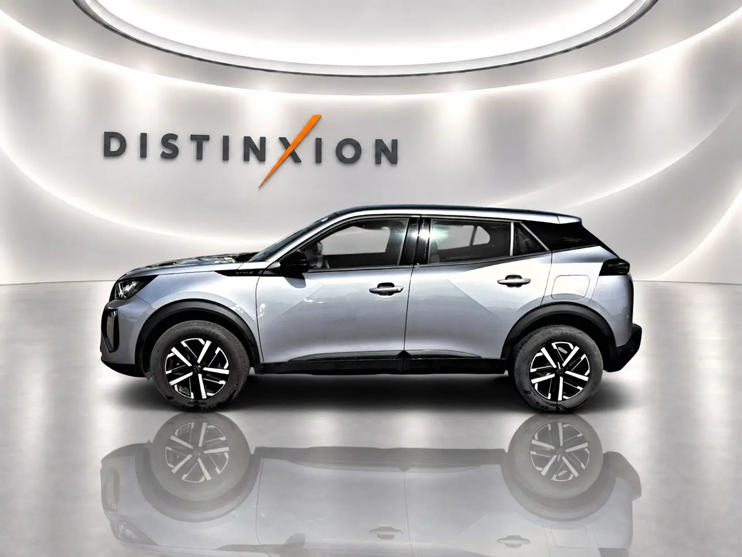 Profil côté gauche du Peugeot 2008 gris 2025 avec jantes noires et toit noir dans un showroom lumineux.
