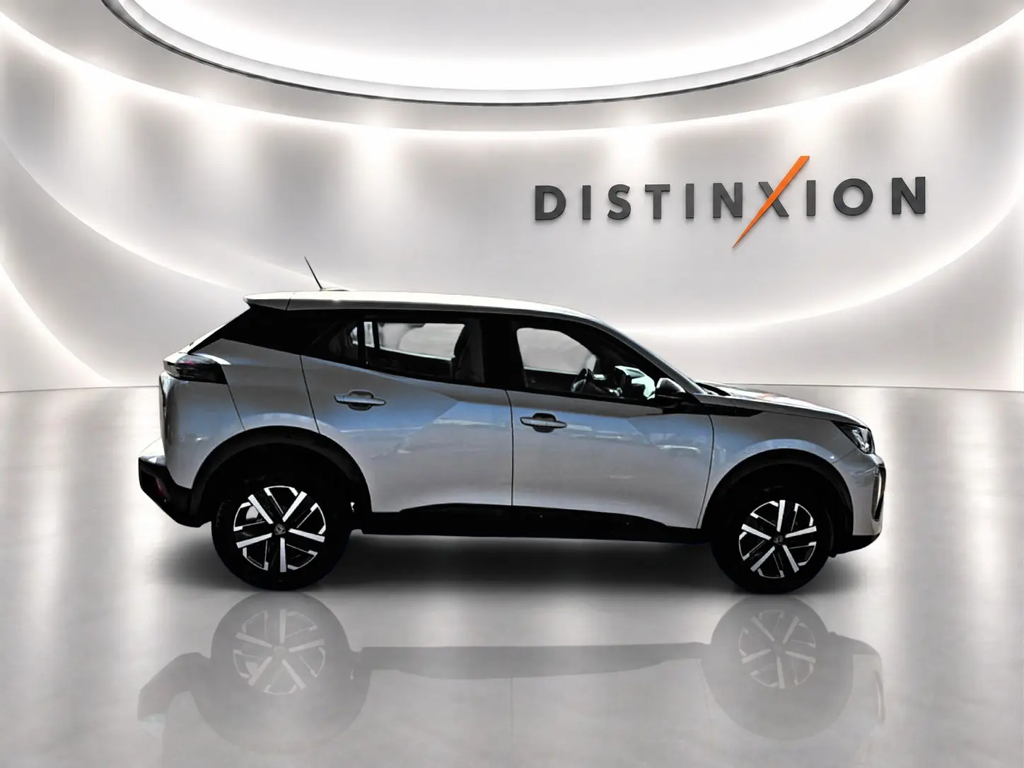 Peugeot 2008 gris en profil droit dans un showroom lumineux avec toit noir et jantes distinctives.