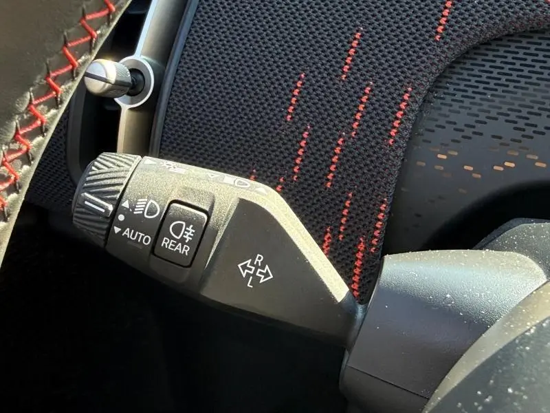 Gros plan sur la commande de phares et clignotants dans l'habitacle du MINI Countryman argenté, avec surpiqûres rouges visibles.