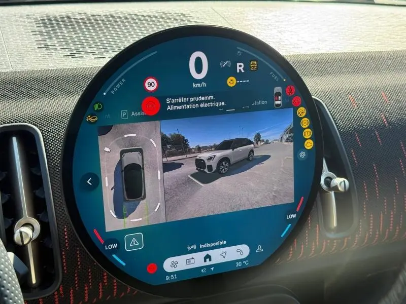 Affichage numérique circulaire montrant la vue 360° et caméra arrière d'une MINI Countryman argentée en stationnement.