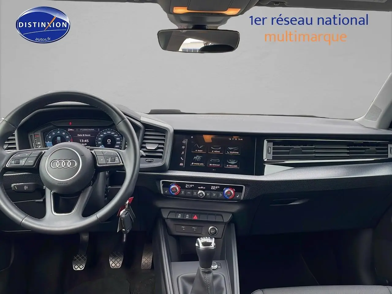 Intérieur noir de l'Audi A1 Sportback 30 TFSI 2022 vu de face, avec tableau de bord digital et volant cuir sport.
