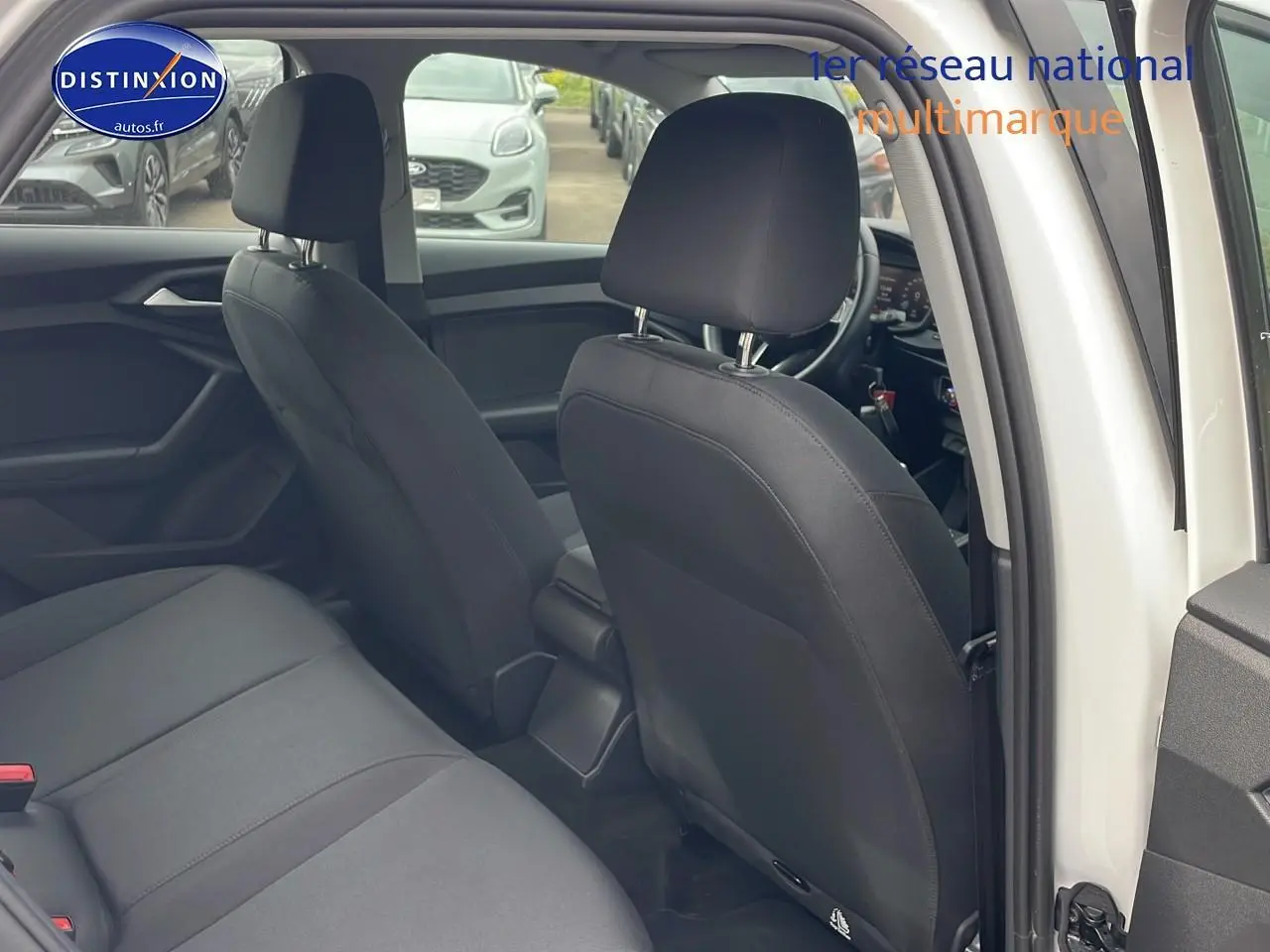 Intérieur arrière de l'Audi A1 Sportback blanc, montrant les sièges noirs et l'ouverture de la porte côté droit.