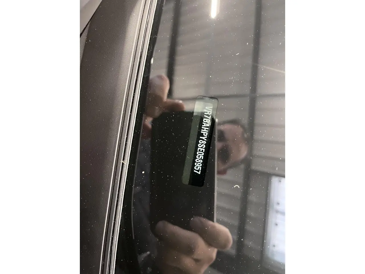 Vue rapprochée du pare-brise avant d'une Citroën C4 noire métallisée, montrant le numéro VIN visible à travers le verre.