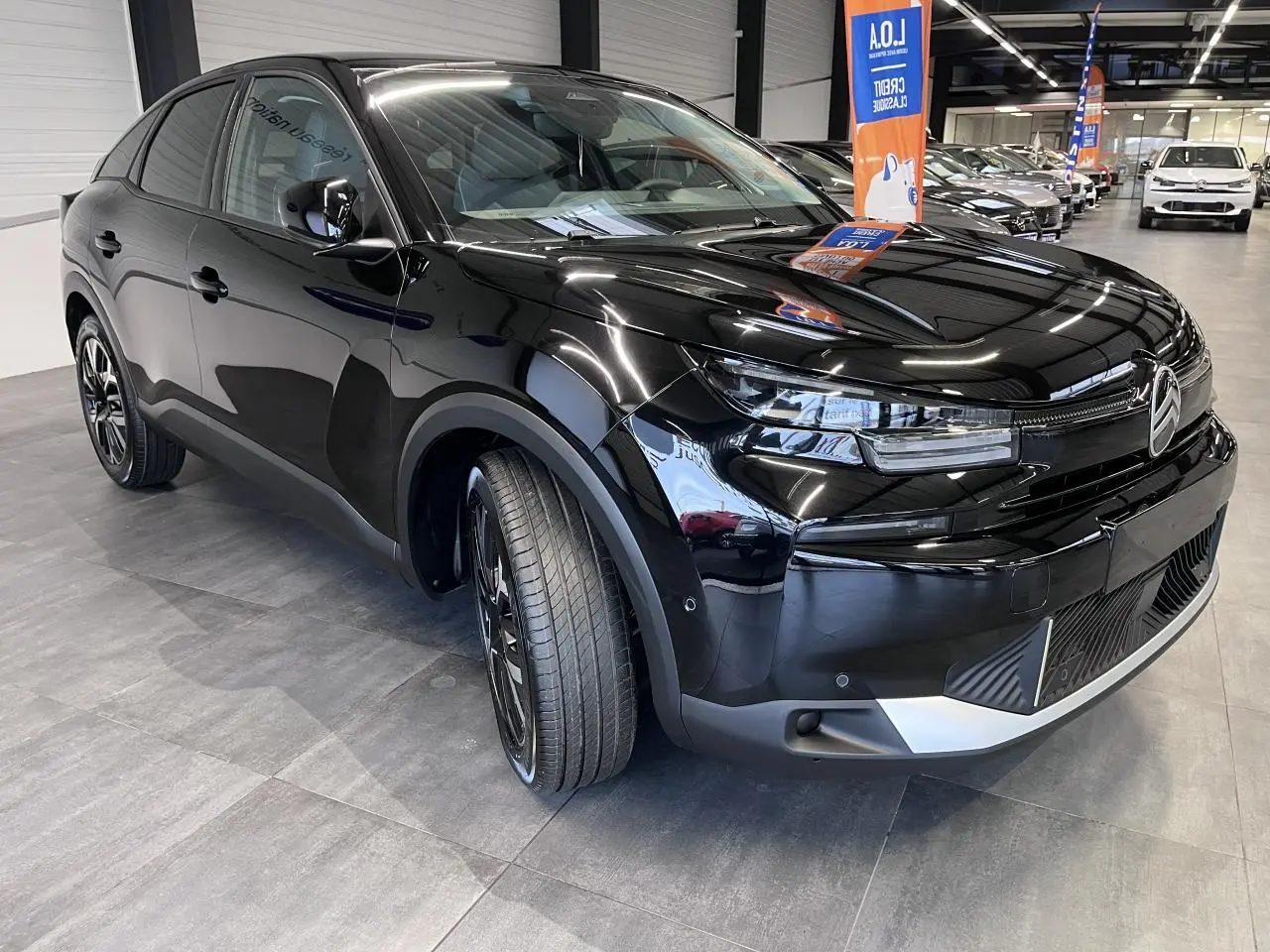 Vue 3/4 avant gauche d'une Citroën C4 noire métal avec jantes alliage et détails chromés au pare-chocs.