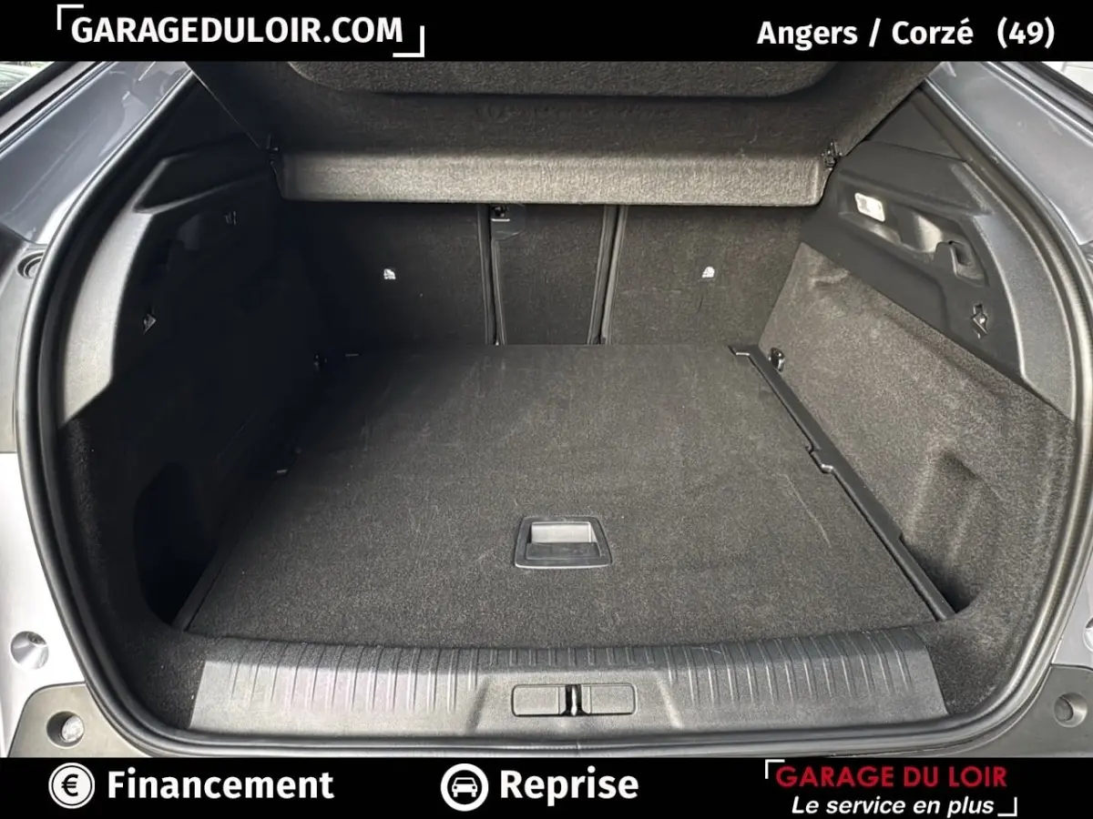 Coffre ouvert vu de l'arrière d'un Peugeot 3008 gris clair 2024, montrant un espace de chargement propre et spacieux.