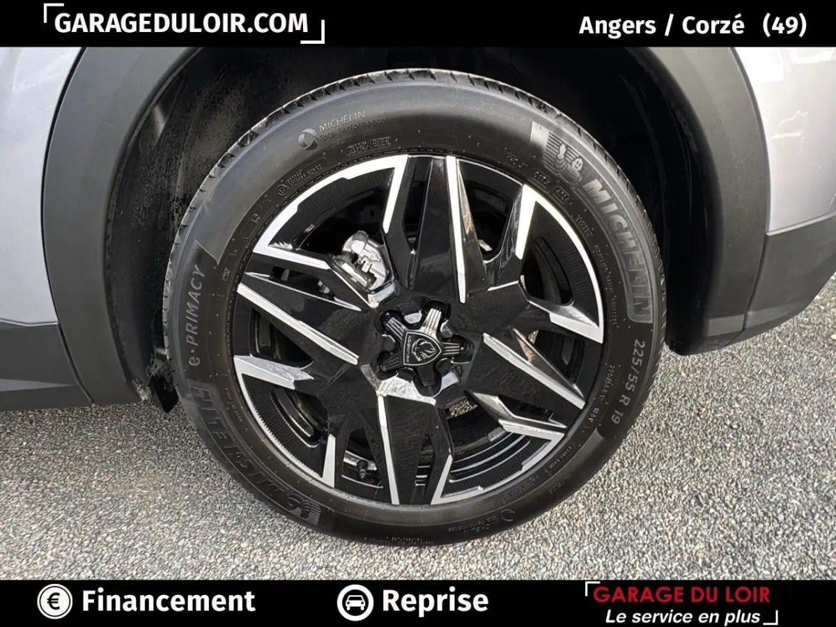 Gros plan sur la roue avant droite d’un Peugeot 3008 gris clair 2024, jante alliage noire et argentée distinctive.