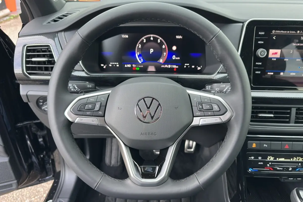 Vue rapprochée du volant cuir multifonctions noir du Volkswagen T-Cross 2025, avec tableau de bord digital et écran central tactile.