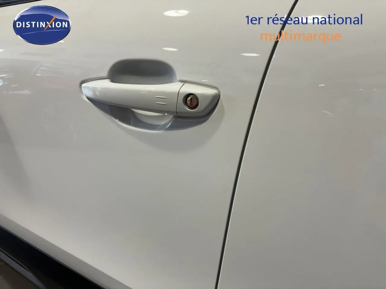 Poignée de porte blanche côté gauche d'une Citroën C4 2022 vue en gros plan intérieur garage.