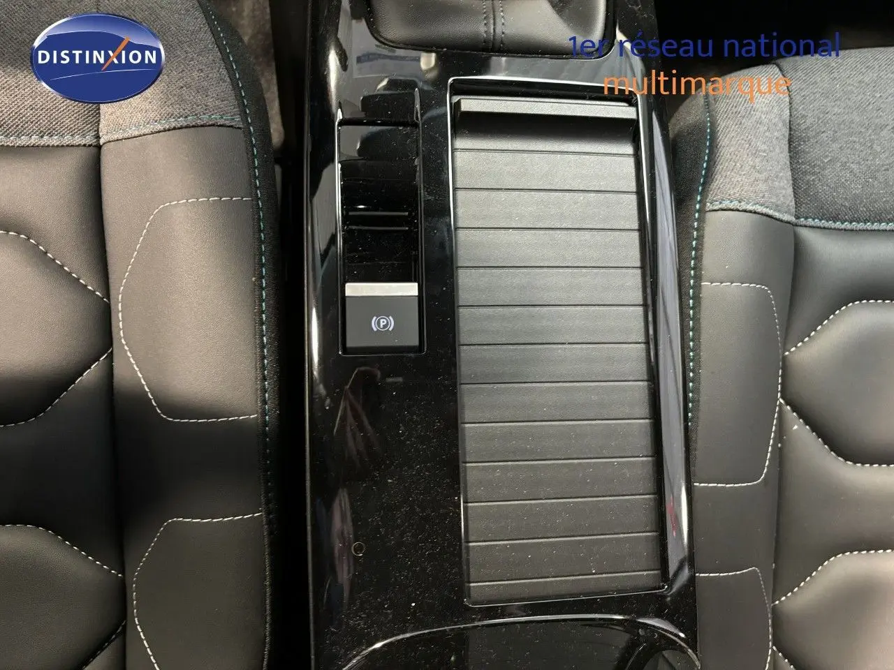 Gros plan sur la console centrale noire et les sièges en tissu gris avec surpiqûres blanches de la Citroën C4 blanche 2022.