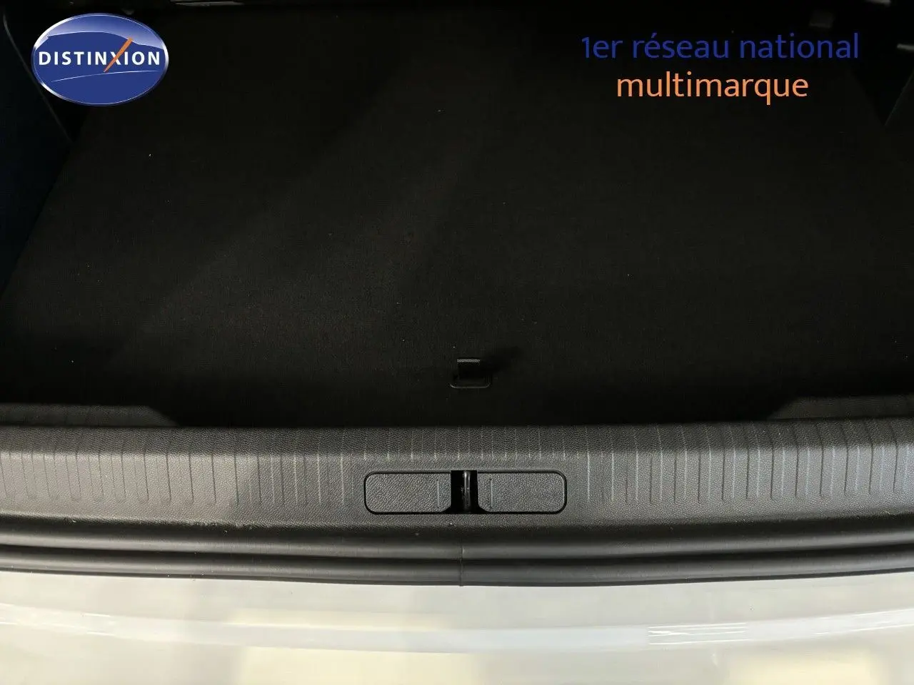 Vue rapprochée de l'ouverture du coffre d'une Citroën C4 blanche, montrant le seuil et l'intérieur noir du coffre.