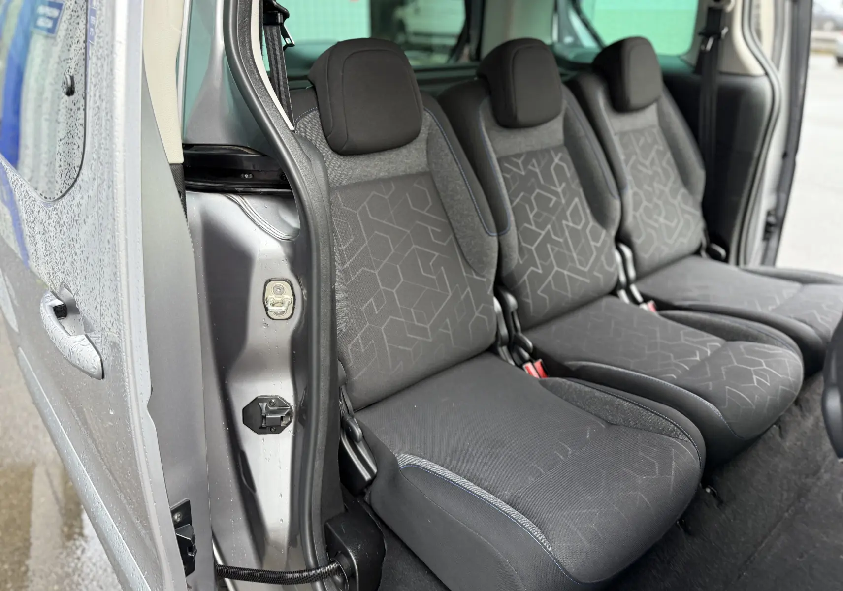 Vue intérieure côté droit sur les sièges tissu gris du Peugeot Partner Tepee 2018 avec porte coulissante ouverte.