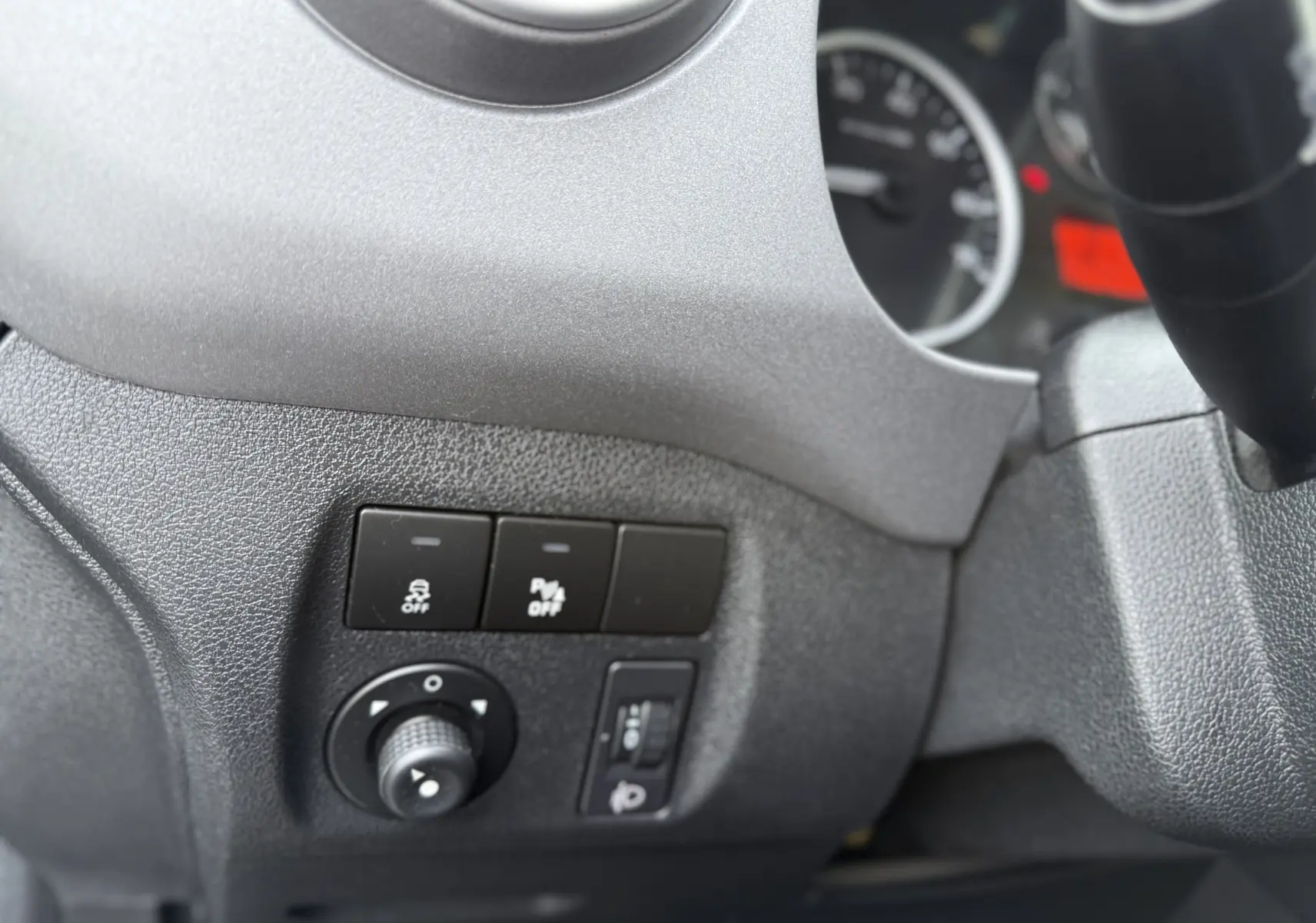 Gros plan sur les commandes à gauche du volant du Peugeot Partner Tepee gris, avec boutons de réglage et tableau de bord partiel.