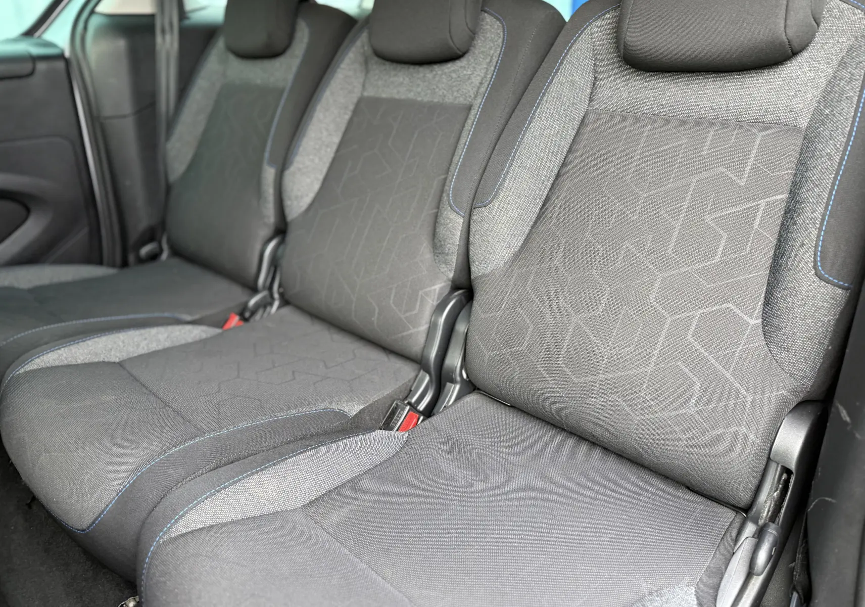 Vue rapprochée des sièges arrière en tissu gris avec surpiqûres bleues du Peugeot Partner Tepee 2018.