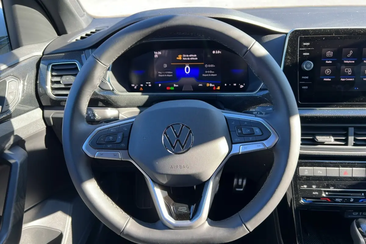 Vue rapprochée du volant cuir multifonctions et du tableau de bord numérique du Volkswagen T-Cross blanc pur 2025.