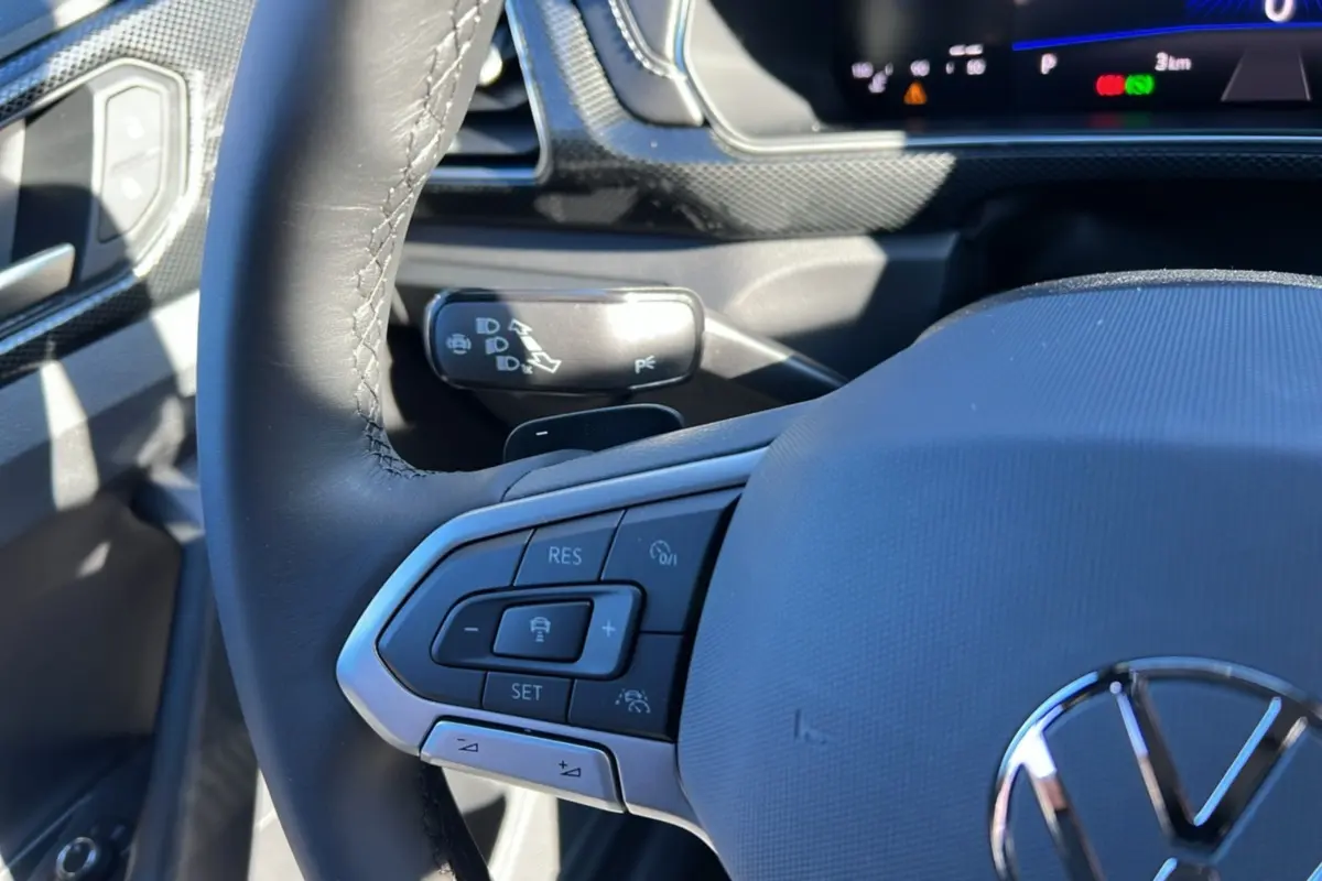 Gros plan sur le volant cuir multifonctions côté gauche du Volkswagen T-Cross blanc pur avec commandes de régulateur de vitesse.