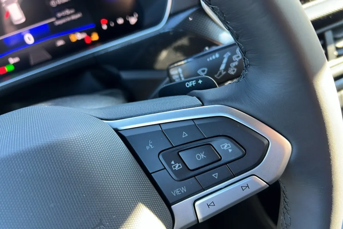 Gros plan sur les commandes multifonctions du volant cuir noir du Volkswagen T-Cross TSI 116 DSG7 R-Line 2025.