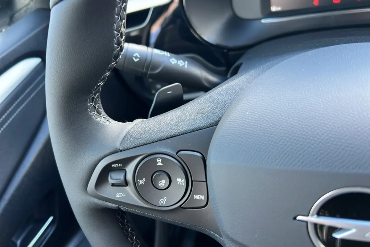 Gros plan sur le volant cuir noir de l’Opel Corsa Hybrid 2026, avec commandes multifonctions et surpiqûres visibles.