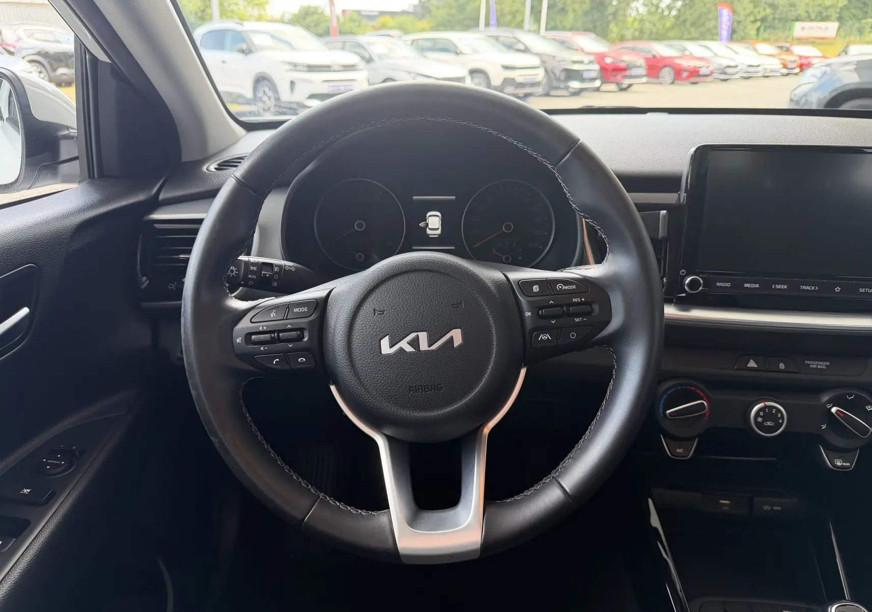 Vue intérieure centrée sur le volant noir de la Kia Stonic 2023, avec tableau de bord et écran tactile visibles.