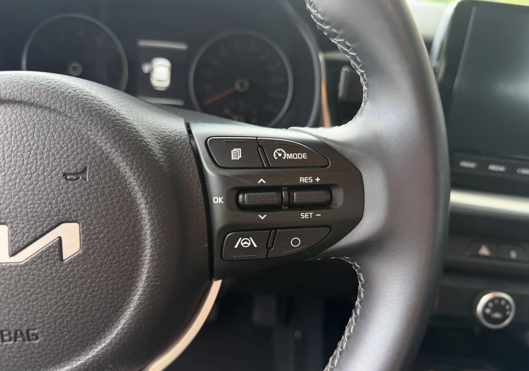 Gros plan sur le volant noir du Kia Stonic blanc 2023, avec commandes de régulateur de vitesse à droite.