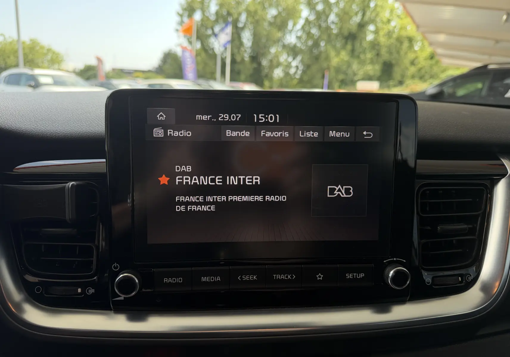 Écran central tactile du tableau de bord d'une KIA Stonic blanc, affichant la radio France Inter en mode DAB.