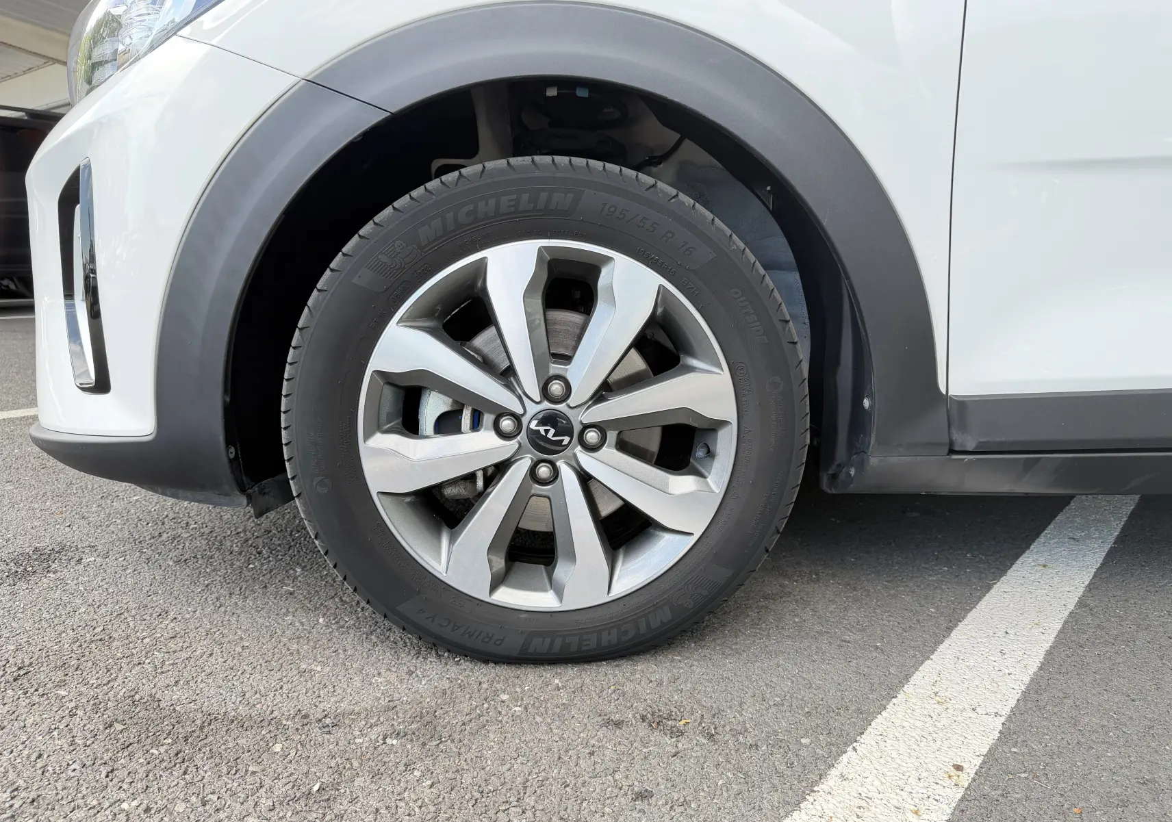 Gros plan sur la roue avant gauche d’un KIA STONIC blanc, mettant en valeur la jante alliage 16 pouces et le pneu Michelin.
