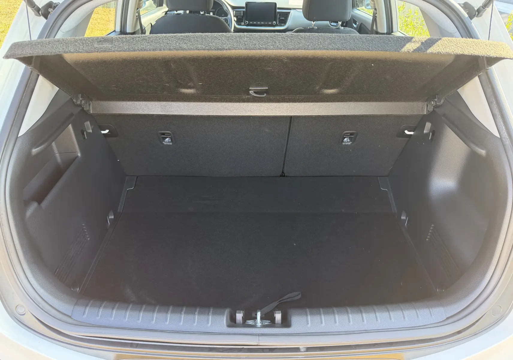 Coffre ouvert du Kia Stonic blanc 2023, vue arrière montrant l’espace de chargement et l’intérieur du véhicule.