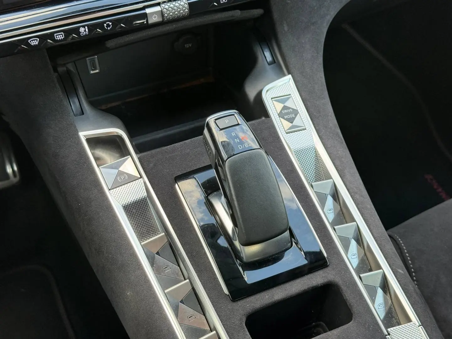 Gros plan sur la console centrale du DS7 E-TENSE 2024, avec levier de vitesse et boutons argentés sur fond noir Alcantara.