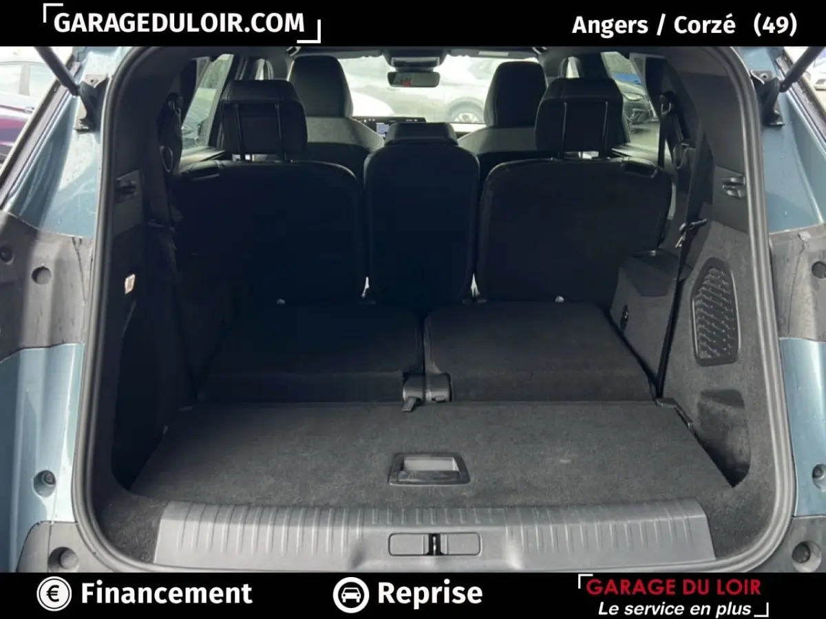 Vue arrière du coffre ouvert du Peugeot 5008 bleu 2024 avec sièges arrière rabattus et espace de chargement plat.