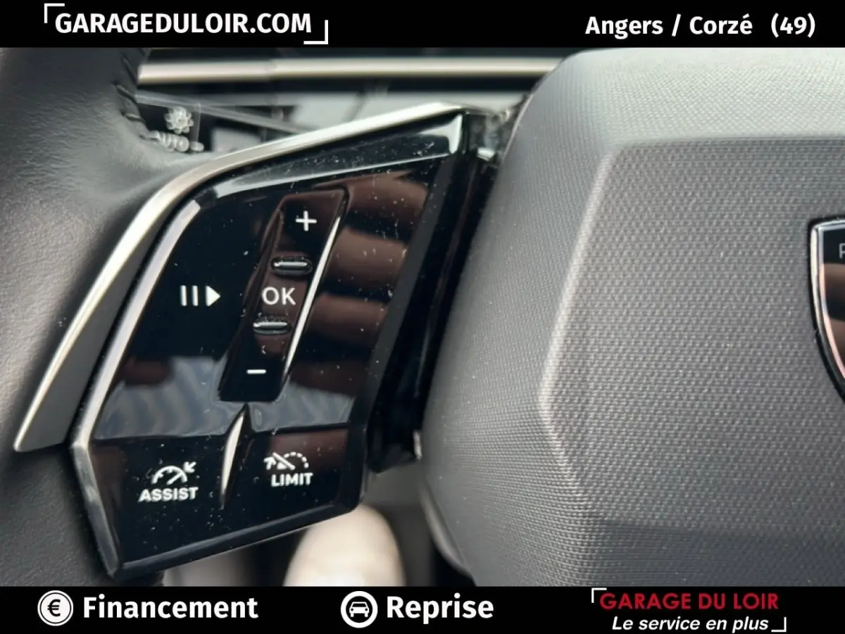 Gros plan sur les commandes au volant noir brillant du Peugeot 5008 bleu hybride 2024, avec boutons d'assistance et limitation.