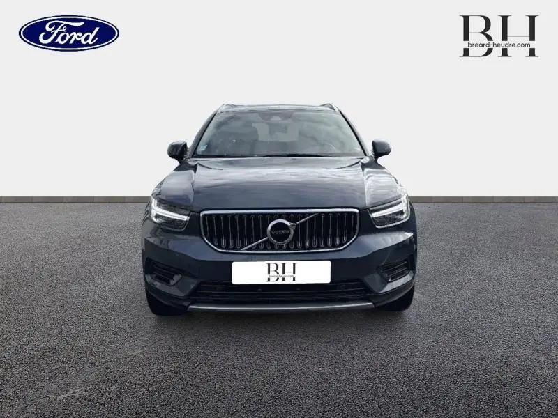 Vue avant d'un Volvo XC40 T4 Recharge bleu Denim, soulignant sa calandre verticale chromée et ses phares LED distinctifs.