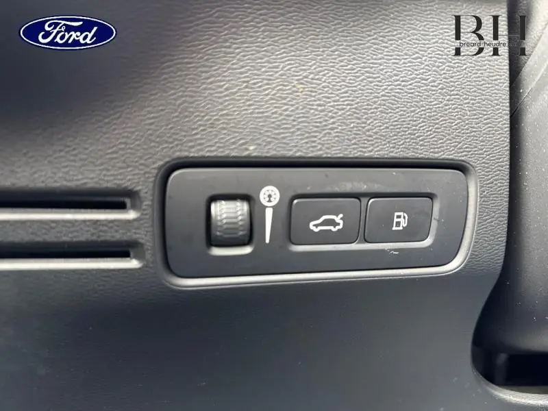 Détail des commandes d'ouverture du coffre et du réservoir sur tableau de bord noir d'un Volvo XC40 Bleu Denim.