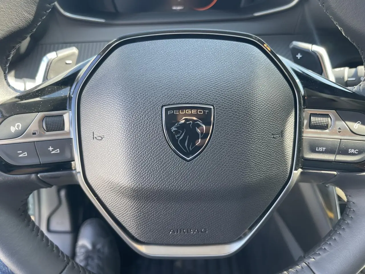 Gros plan sur le volant compact cuir noir avec logo Peugeot Lion chromé du 208 New II 2024 noir Onyx