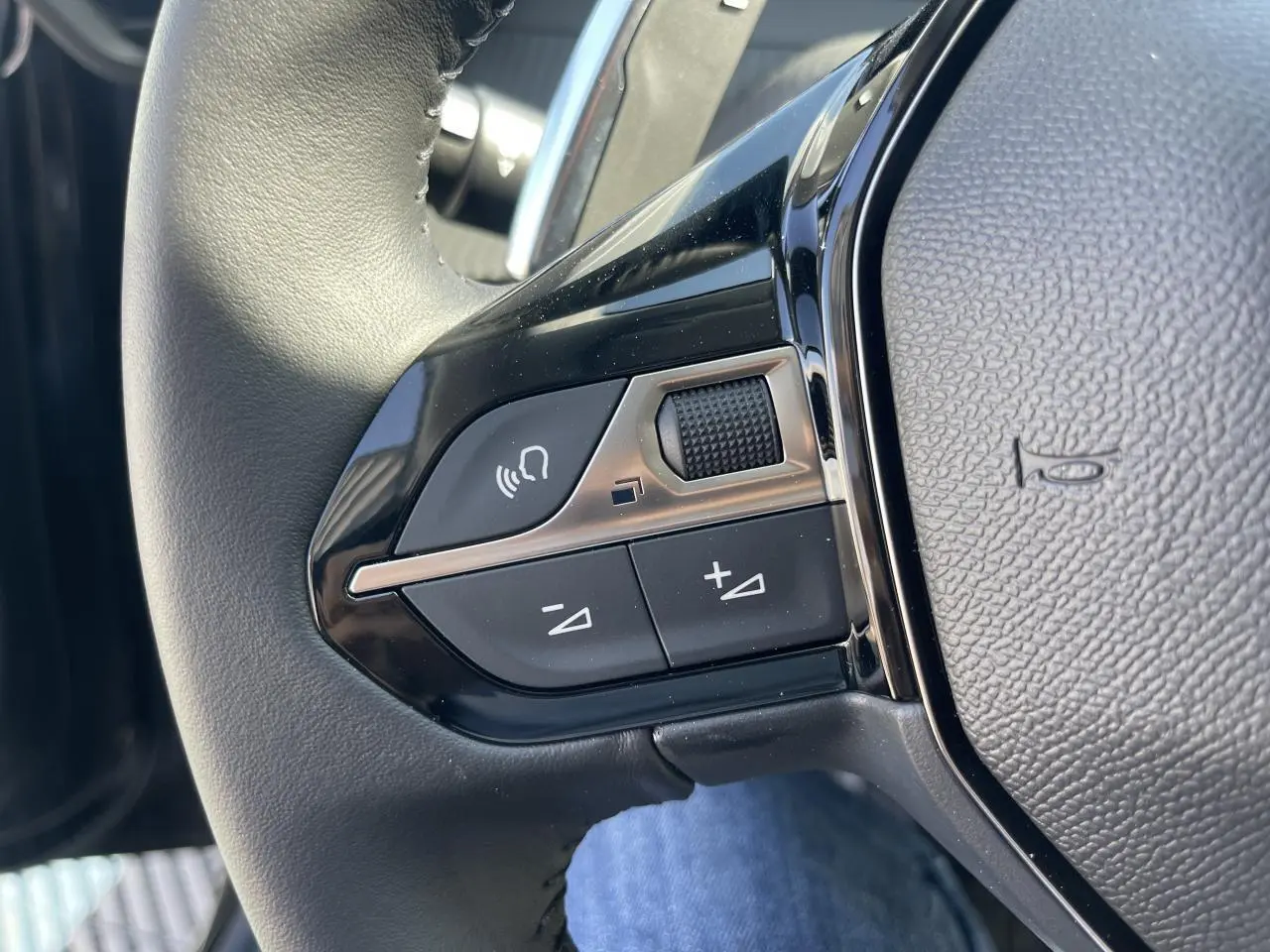 Gros plan sur les commandes vocales et volume du volant cuir noir du Peugeot 208 New II 2024.