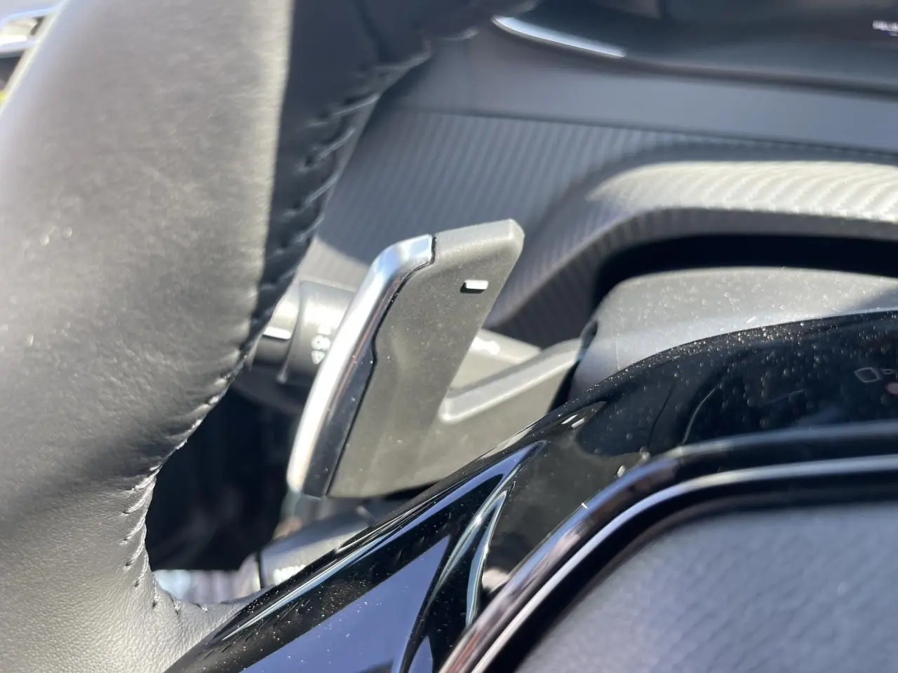 Gros plan sur la palette de changement de vitesse côté gauche du volant cuir noir du Peugeot 208 Noir Onyx 2024.