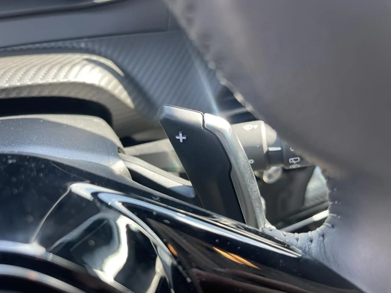 Gros plan sur la palette de changement de vitesse + côté droit du volant cuir du Peugeot 208 noir Onyx 2024.